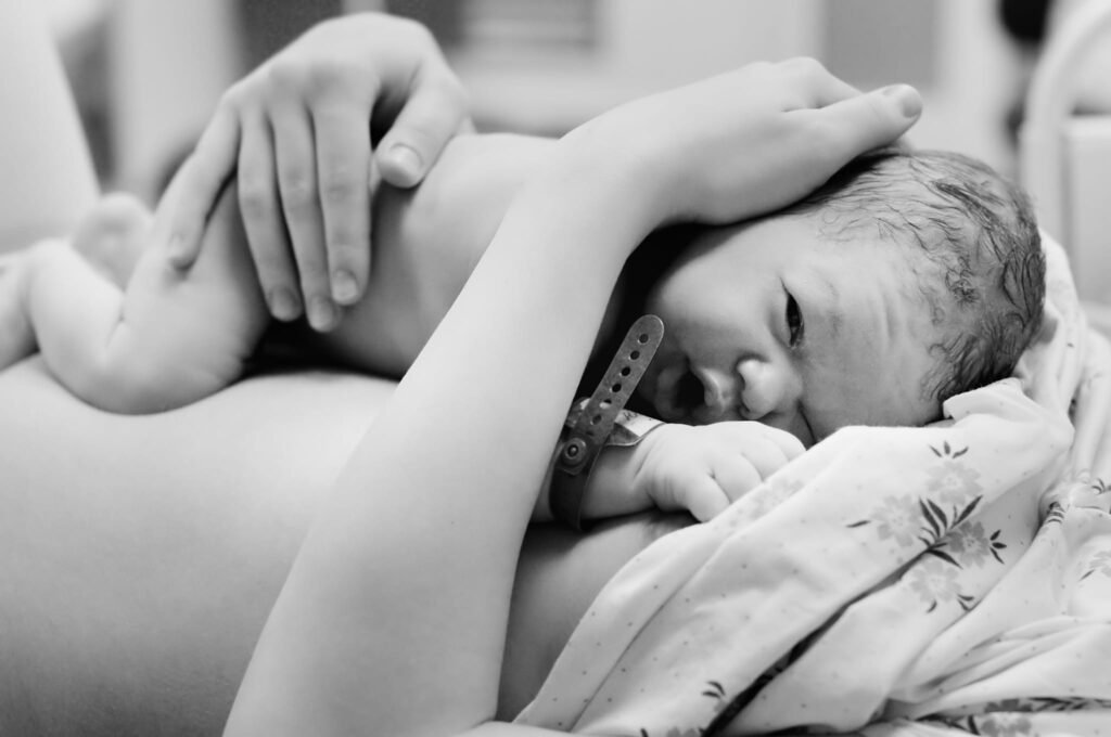 A newborn baby doing skin-to-skin care also known as the breast crawl after birth. Evidence Based Babies.